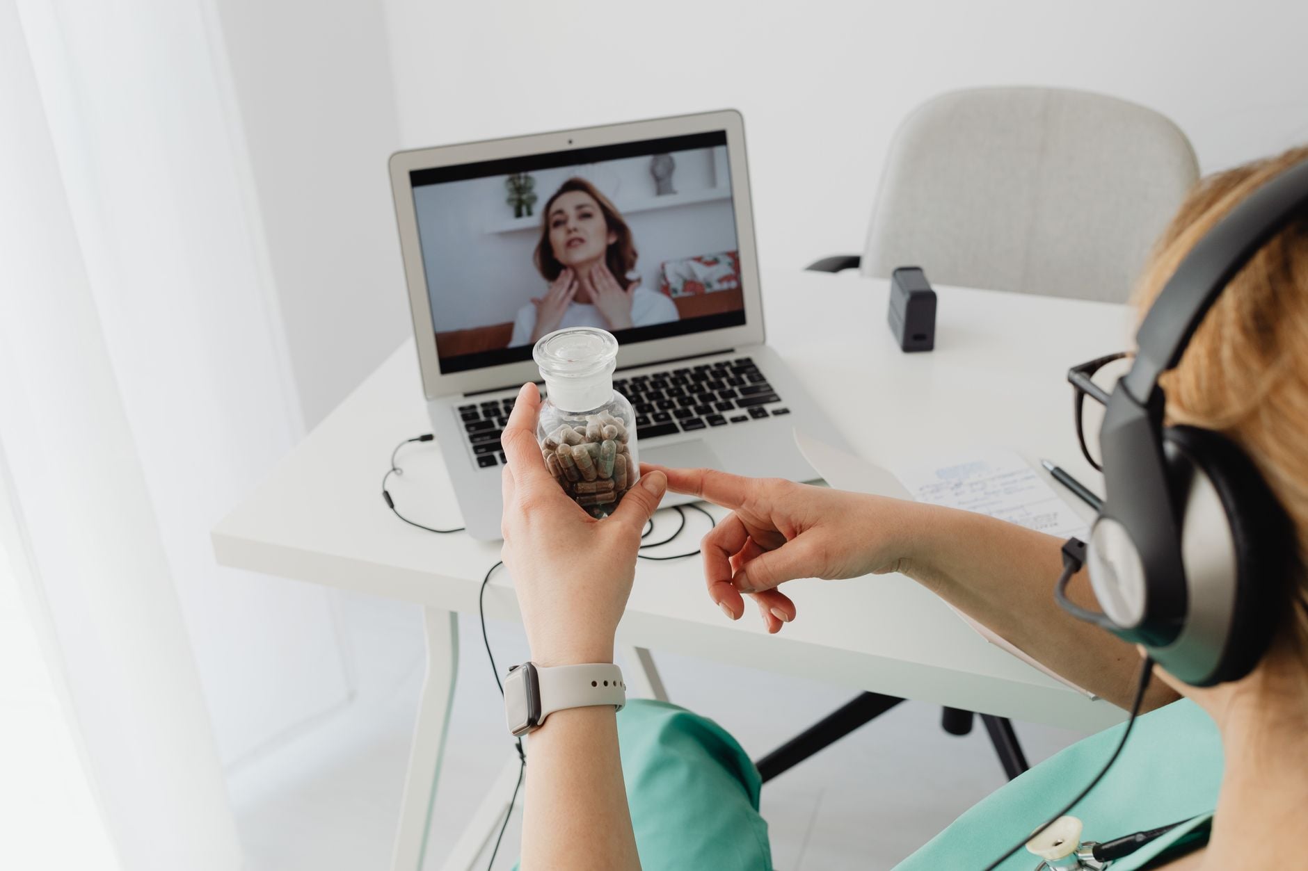 Person holding small potted cactus during video call with woman on laptop screen, wearing headphones
